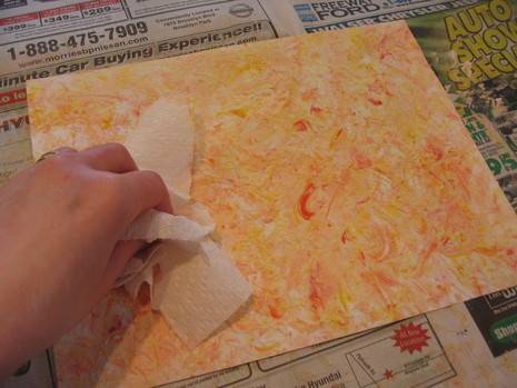 Person blotting paper with paint and paper towel.