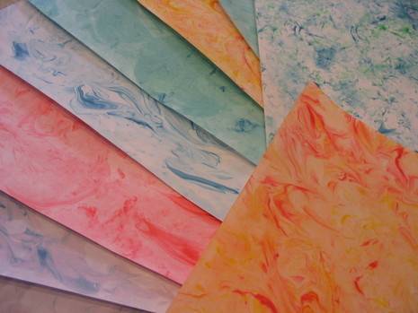 Several sheets of tie-dyed paper in blue, red, green, and orange.