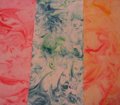 Tie-dyed paper in three different colors; pink, blue and orange.