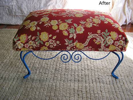 An overstuffed bench with red fabric and yellow flowers stands on curved blue legs.