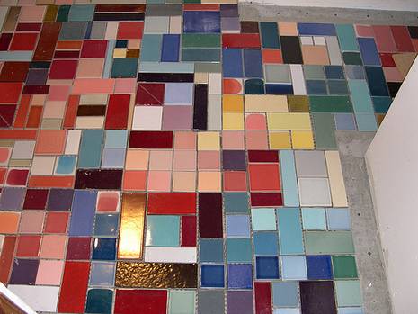 Tile pieces of different colors and sizes laid out on a floor.