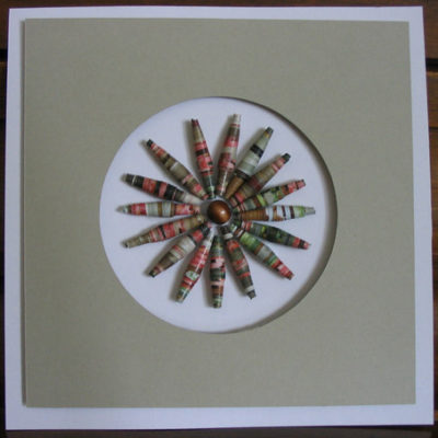 A brown picture has a colorful pinwheel of beads.