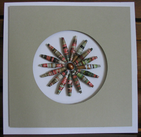 A brown picture has a colorful pinwheel of beads.
