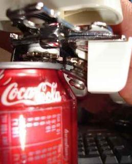 Red Coca Cola can being opened with a can opener.