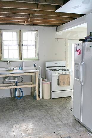 Basic sink next to stove which is by a refrigerator in a kitchen.