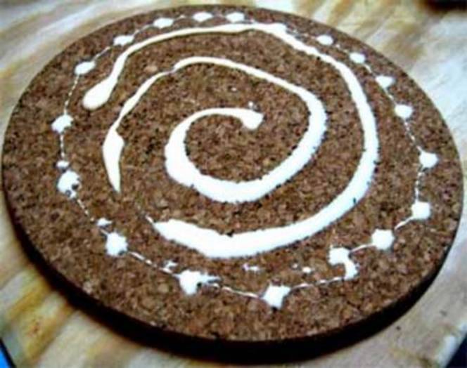 A large circular piece of cork board covered with a large swirl of glue.