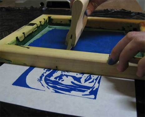 A person is printing man face with blue color with silkscreen printing.