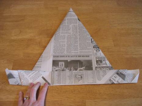 A person is folding a boat out of a newspaper.