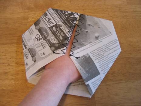 Man put his left hand inside the folded news paper.