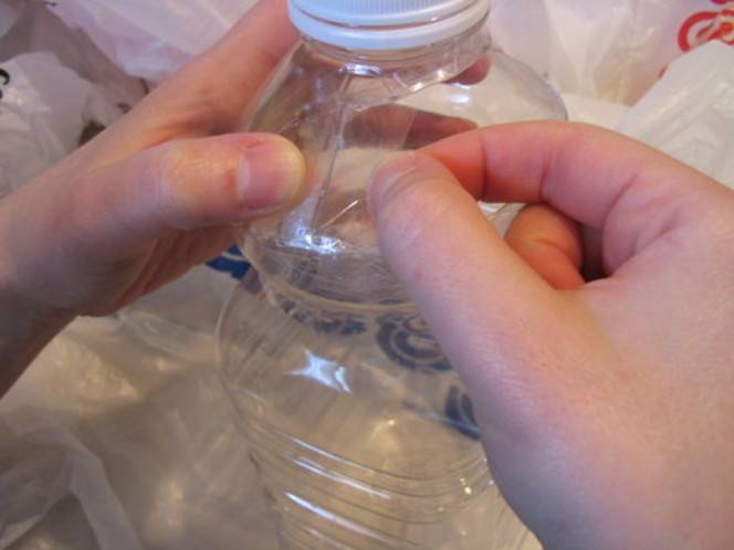 A person is putting something on a clear plastic bottle.