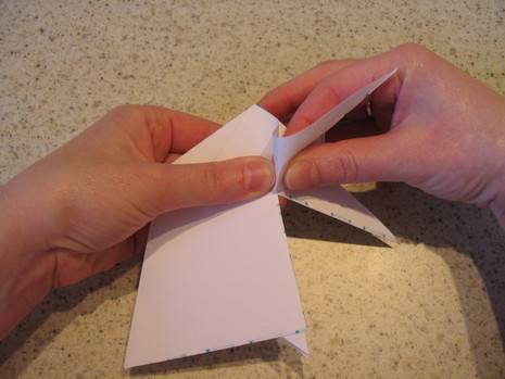 A person is folding a white piece of paper.