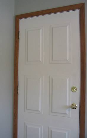 A white door with brown trim against a white wall.
