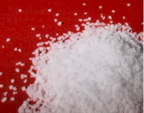 Salt granules laying on top of a bright red surface.