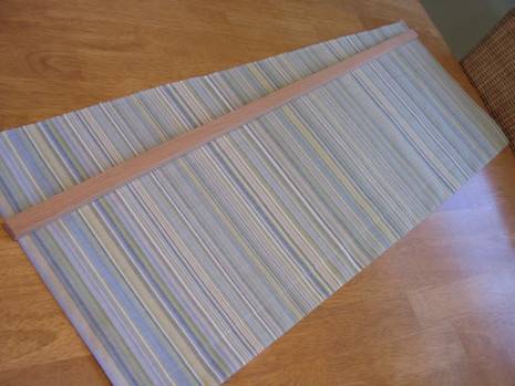 A striped, long window treatment on a table.