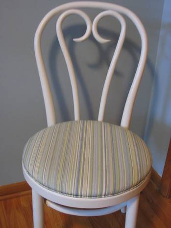 White chair with a striped padded seat sits on hardwood floor against a blue wall.