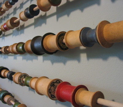 Multicolored wooden spools are stored in straight lines.