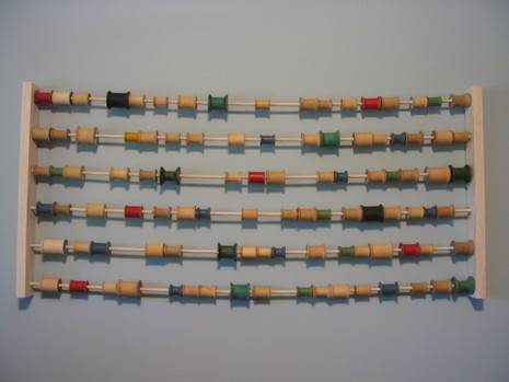 A six row holder filled with spools of different colored thread.