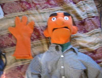 An orange puppet lying down next to orange gloves