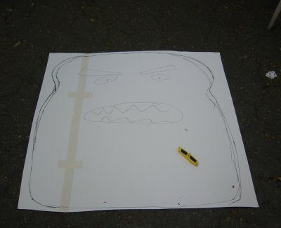 Large white paper on the floor with a large bread slice drawn on it with pencil.