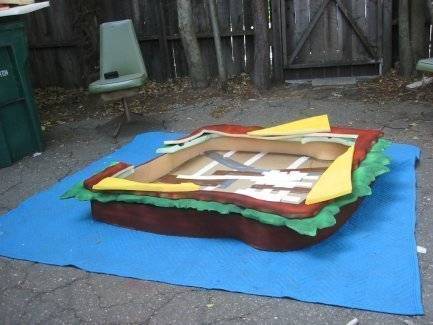 Foam sandwich costume on top of blue tarp.