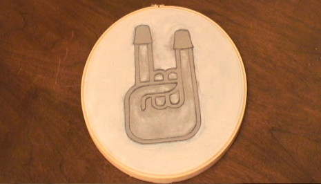 A round tan object with a hand holding up the devil sign.