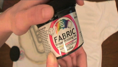 A person is holding a container of screen printing ink.