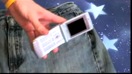Person is showing his mobile phone and a jeans pant is in the background.