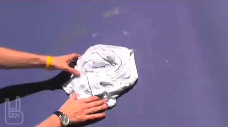 Person balling up a white t-shirt so that it is bunched up.