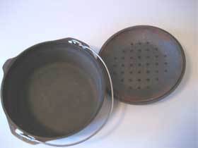 A cast iron pot and lid are sitting on the floor.