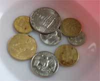 Several different coins in a white dish.