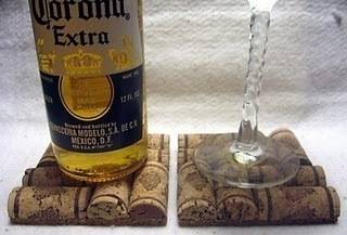 A bottle of Corona and a wine glass both on top of a cork coaster.