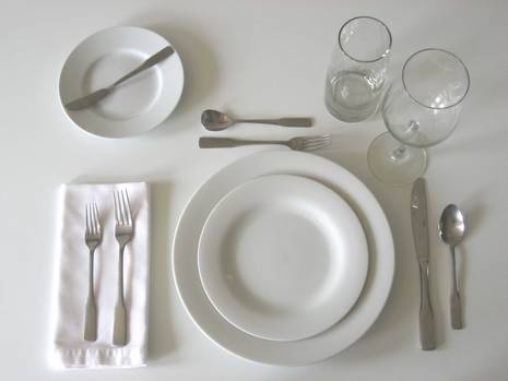 A full table placesetting with white plates and a white napkin.