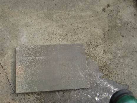 A grey plate is sitting on the concrete.