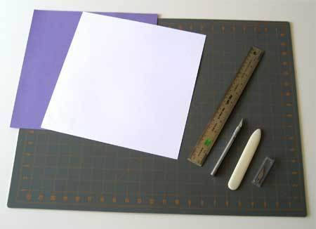 Purple and white paper next to ruler and chalk on top of black graph surface.
