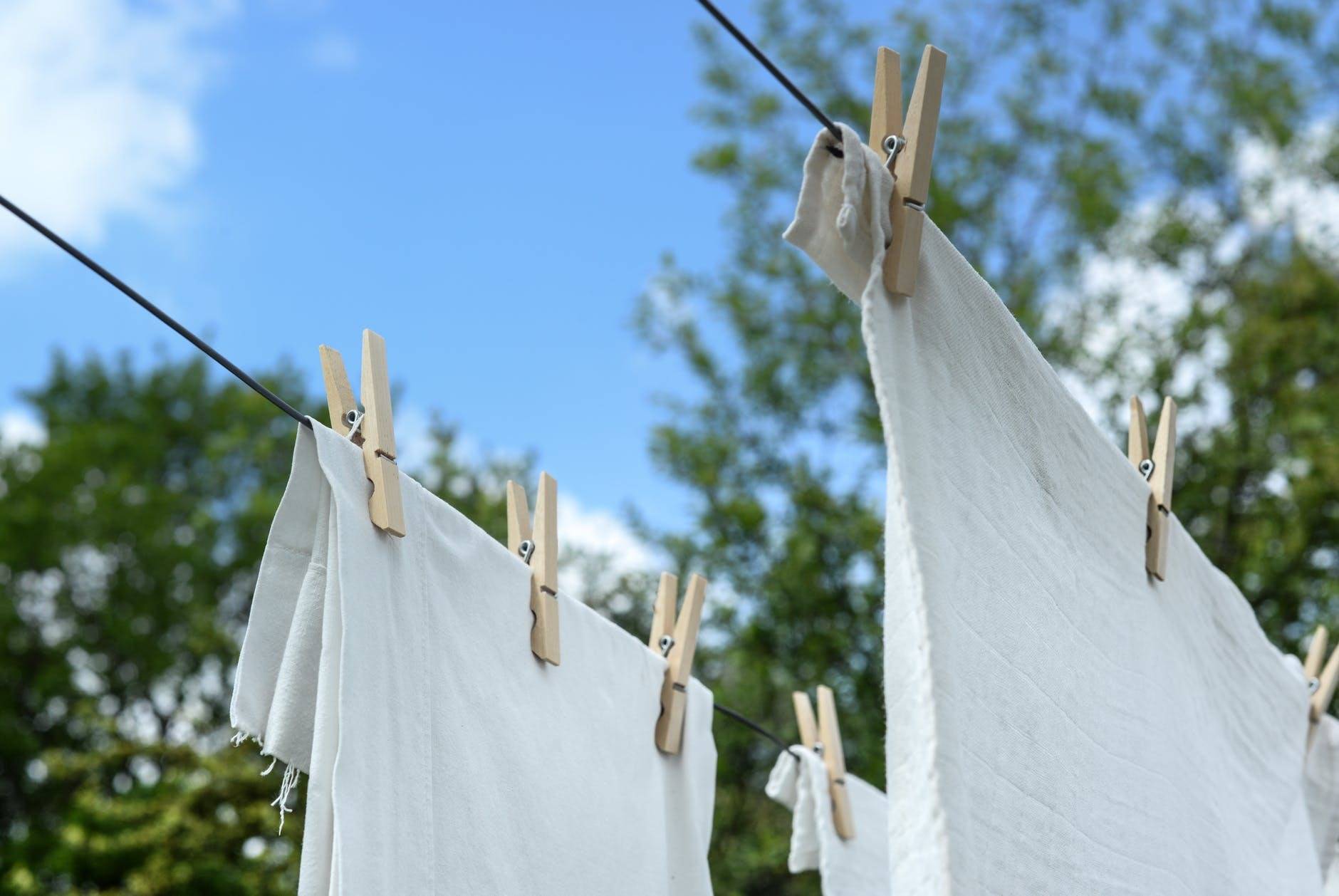 Some fabric sheets on a clothesline held up by several clothespins.