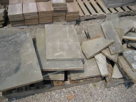 Rectangular ceramic tiles next to bricks stacked on wood pallet.