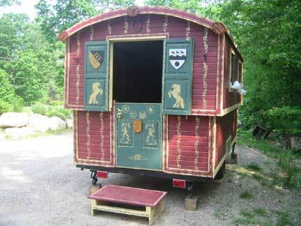 A red camper bed with a green door and yellow rearing horses on the green shutters.