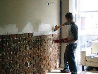 A man installs a brick wall.