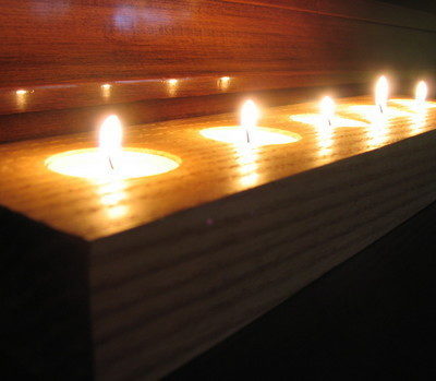 Group of tea candles in wooden holder.