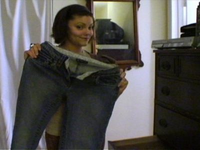 A smiling woman standing with a jeans in front of the mirror.