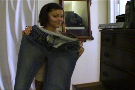 A smiling woman standing with a jeans in front of the mirror.