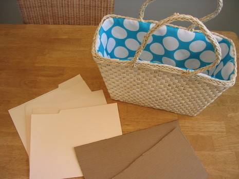 A wicker handbasket with blue and white polka dot interior next to a bunch of manila pocket folders.