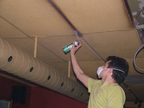 A man repairing a stained ceiling with a spray bottle.
