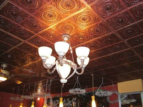 Chandeliers hang from a decorative tin ceiling.