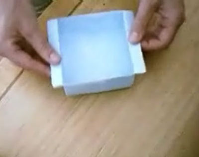 A person is folding a paper and make it as a paper bowl.