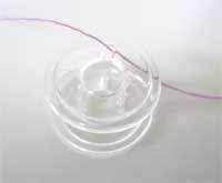 Transparent plastic bobbin with thread.