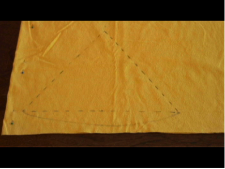 A piece of yellow cloth pinned to a board with a triangular sphere pencil marked on it.