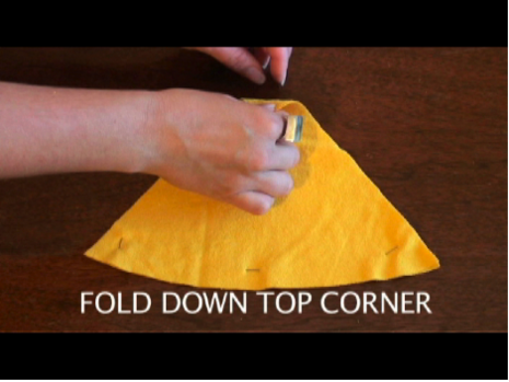 Two hands manipulation yellow fabric that is cut into a rounded triangle.