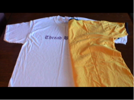 A yellow t-shirt folded widthwise half-covering a lighter blue t-shirt.