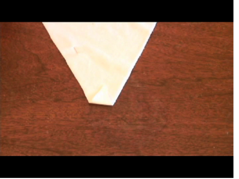 A white triangle of fabric on a brown surface.